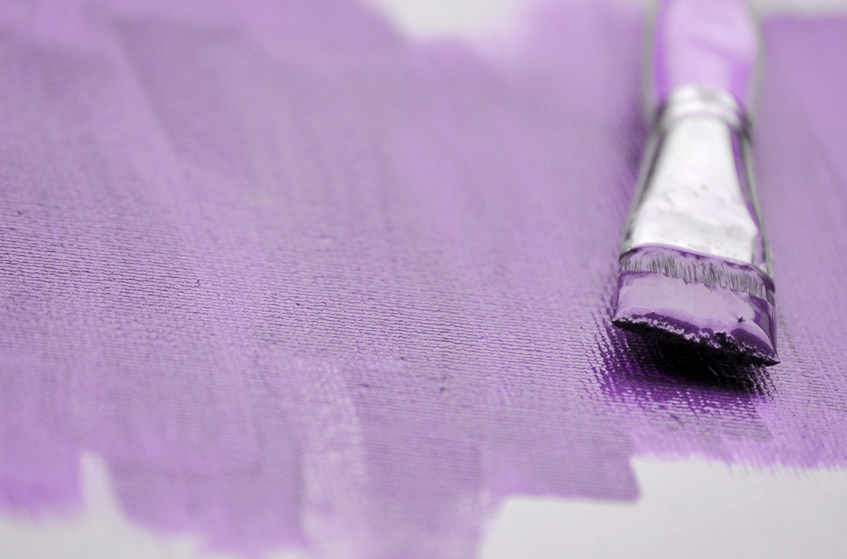 détail toile de peinture avec un fond violet avec pinceau posé dessus