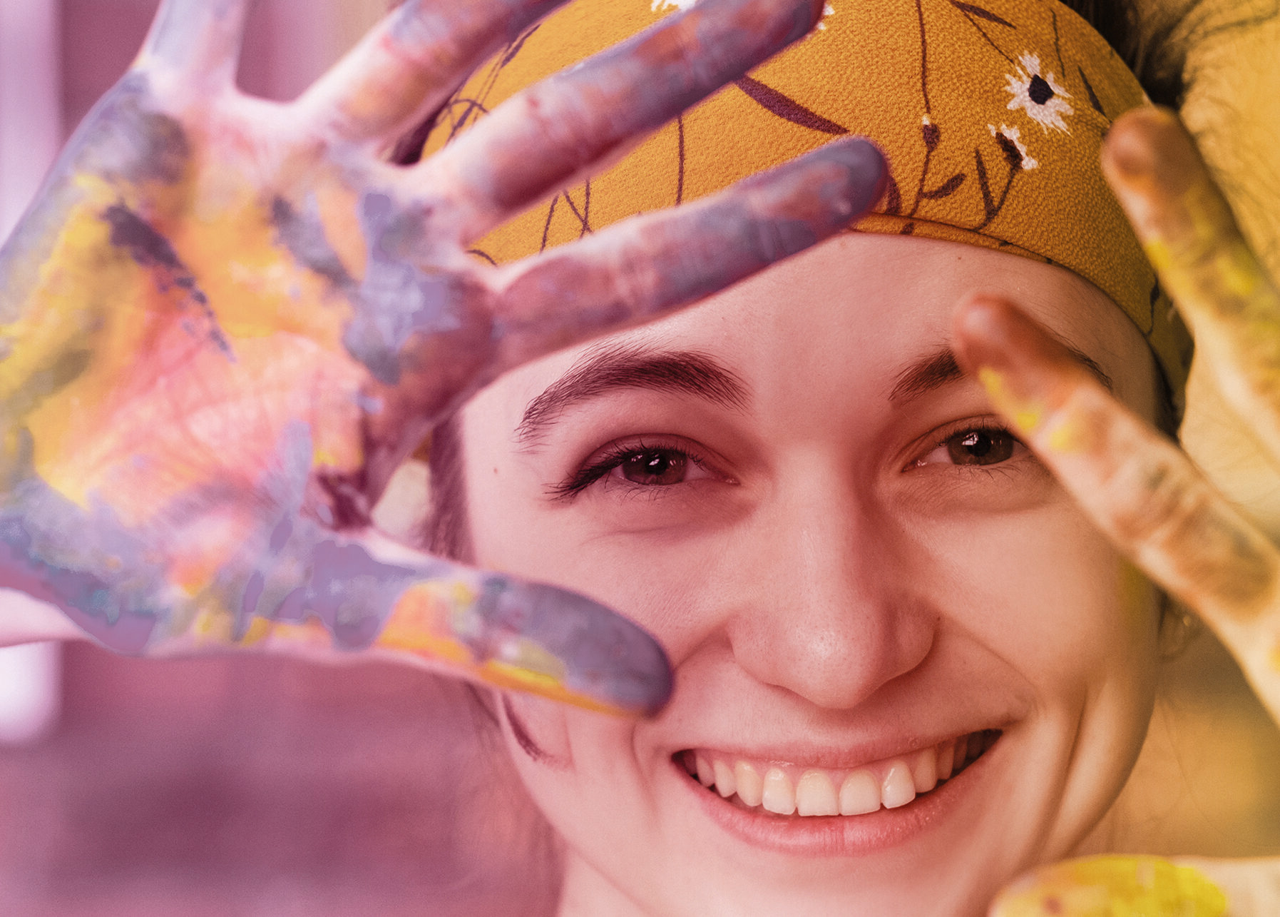 smiling woman in art therapy session showing her hands full of paint