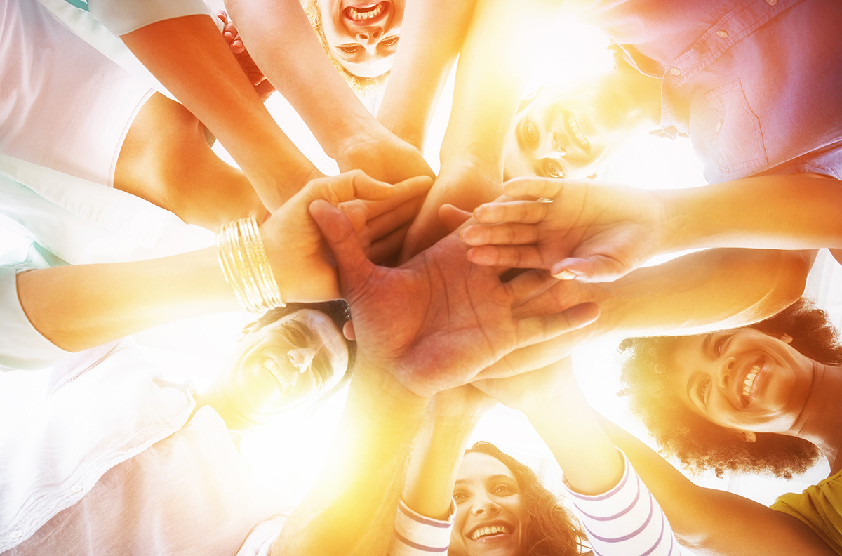 group of people stacking their hands on top of each other as a sign of cohesion